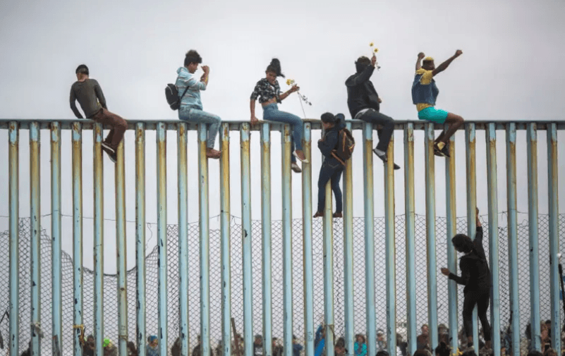 Imagen de la frontera México - EE.UU con los migrantes en el muro